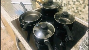 A kitchen with four black pots and pans on a stove. - Forset Court (London)