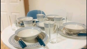 A dining table set with white plates, bowls, and cups, along with cutlery and a glass. - Forset Court (London)
