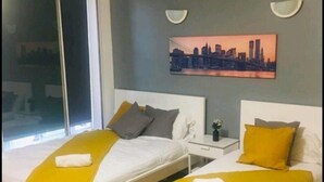 A modern hotel room with two single beds, a large window, and a cityscape painting on the wall. - Forset Court (London)