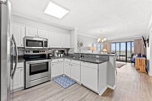 A modern kitchen with white cabinetry, stainless steel appliances, and a large island.