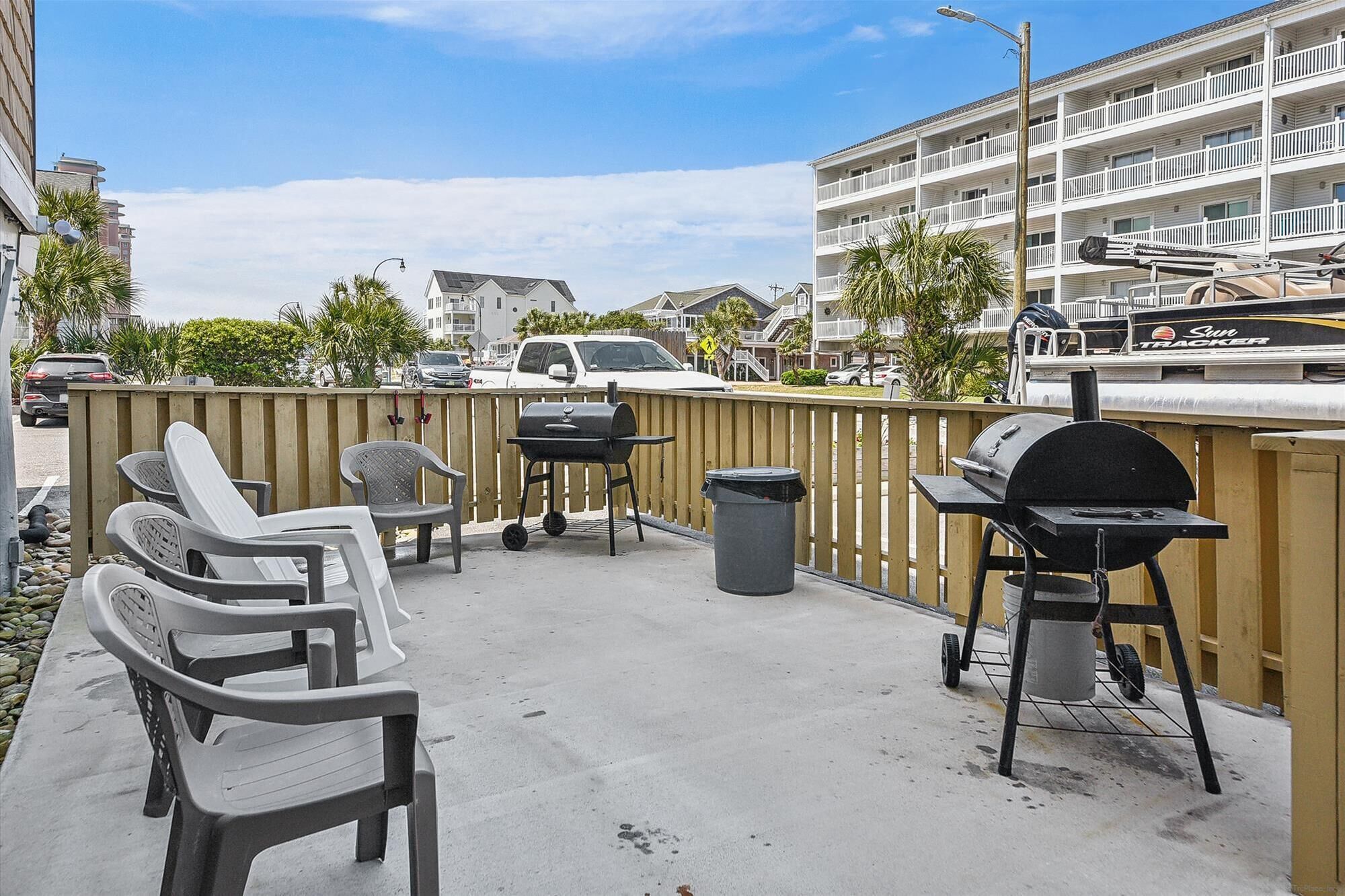 Een balkon met tuinmeubilair, een barbecue en een afvalbak.