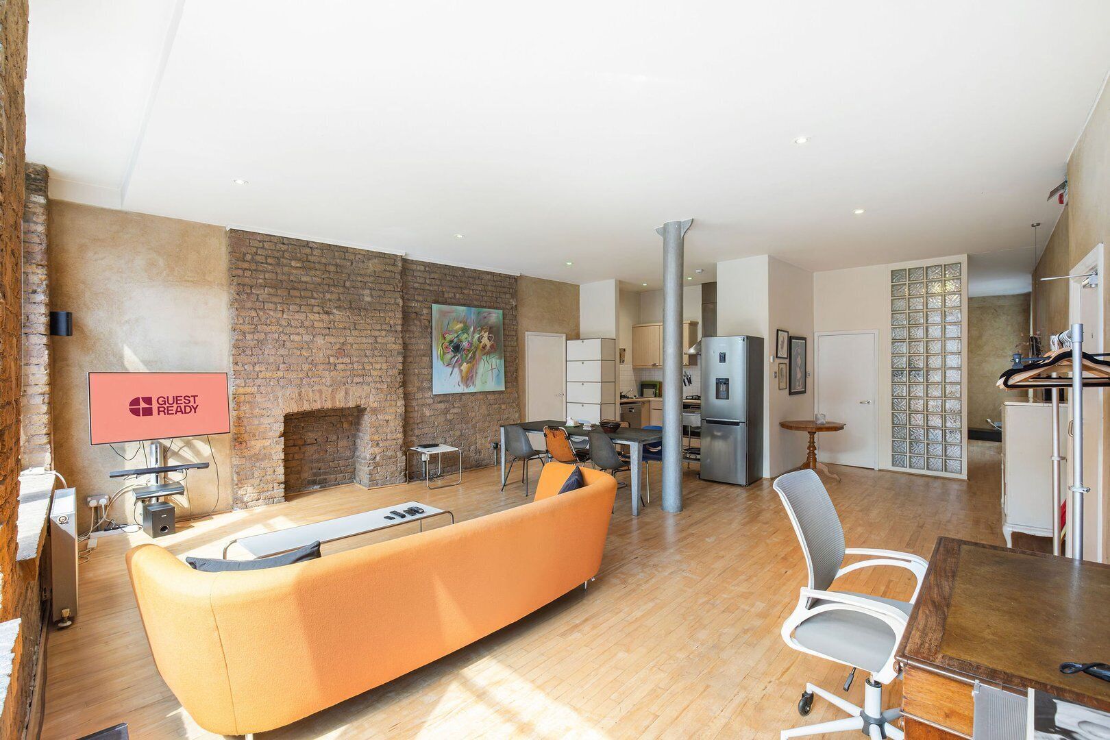 A modern living room with a brick wall, a fireplace, a dining area, and a kitchen.