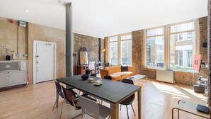 A modern interior with a dining area, a sofa, and large windows.