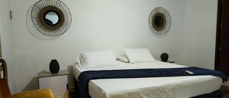 A bedroom with a bed, two nightstands, a chair, and two wall-mounted mirrors.