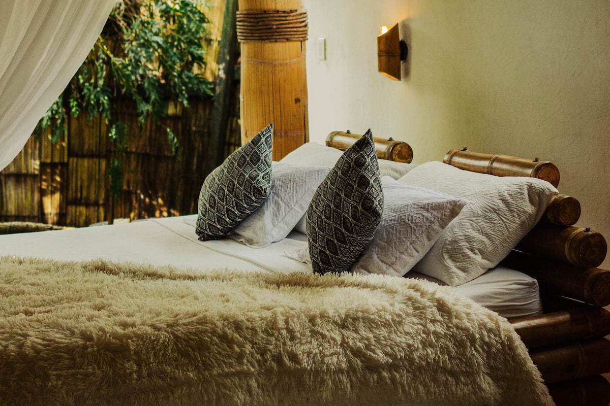 A bed with white linens, two patterned pillows, and a fluffy blanket.