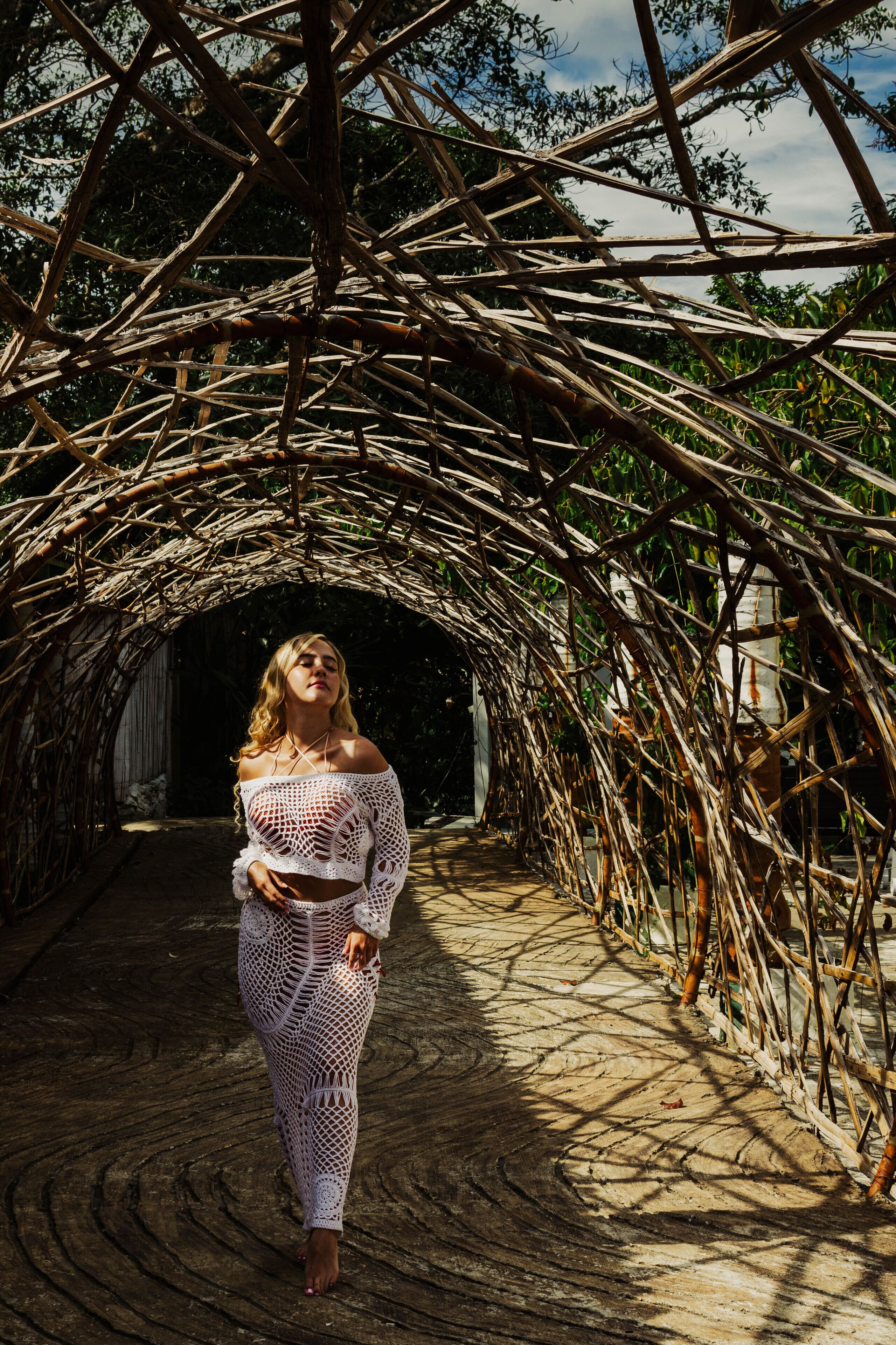 A person walking through a bamboo archway.