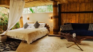 Quarto com cama, sofá, mesa de madeira e uma janela grande.