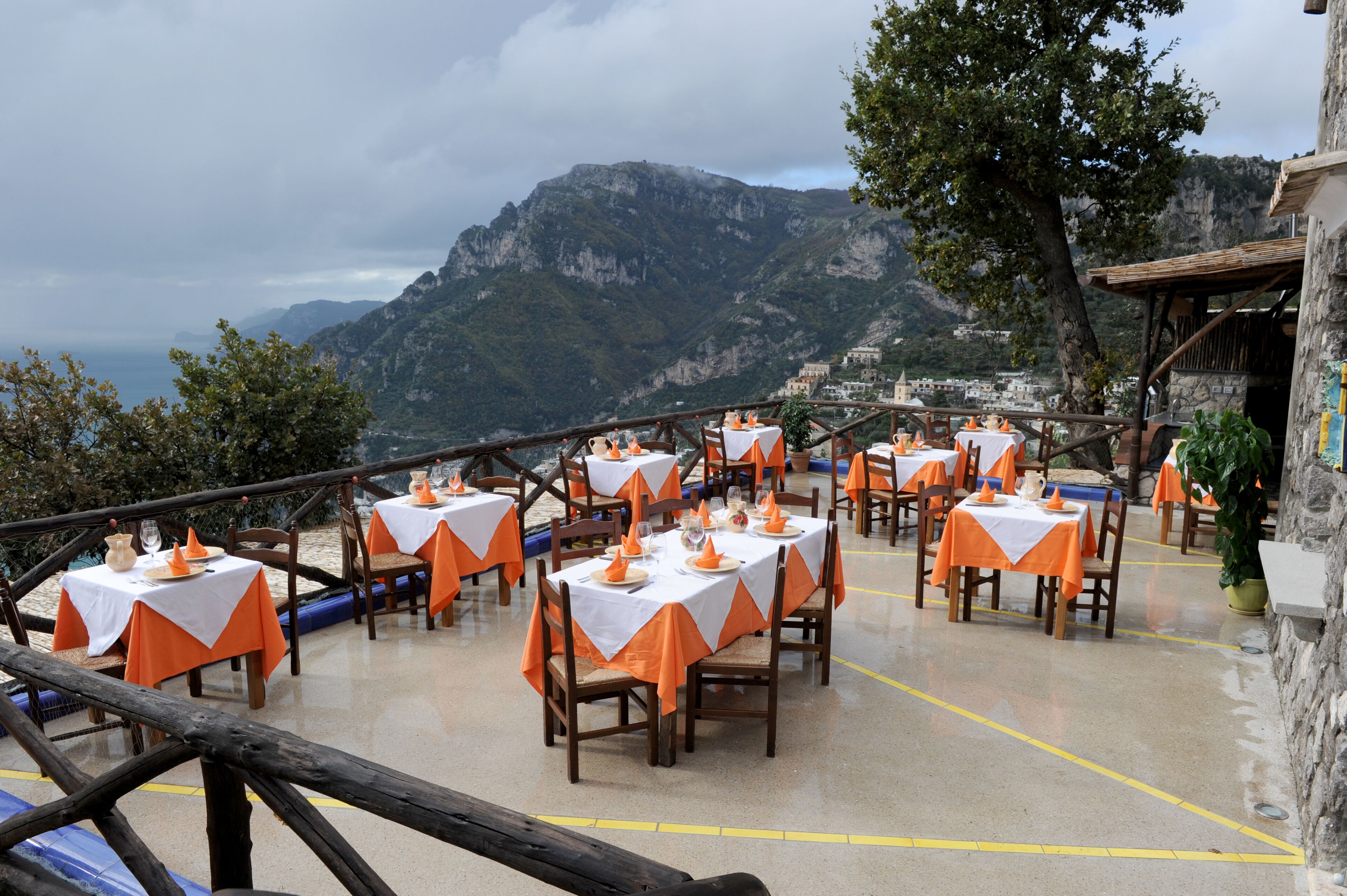Un área de comedor al aire libre con mesas preparadas para los comensales, con vistas a un paisaje montañoso.
