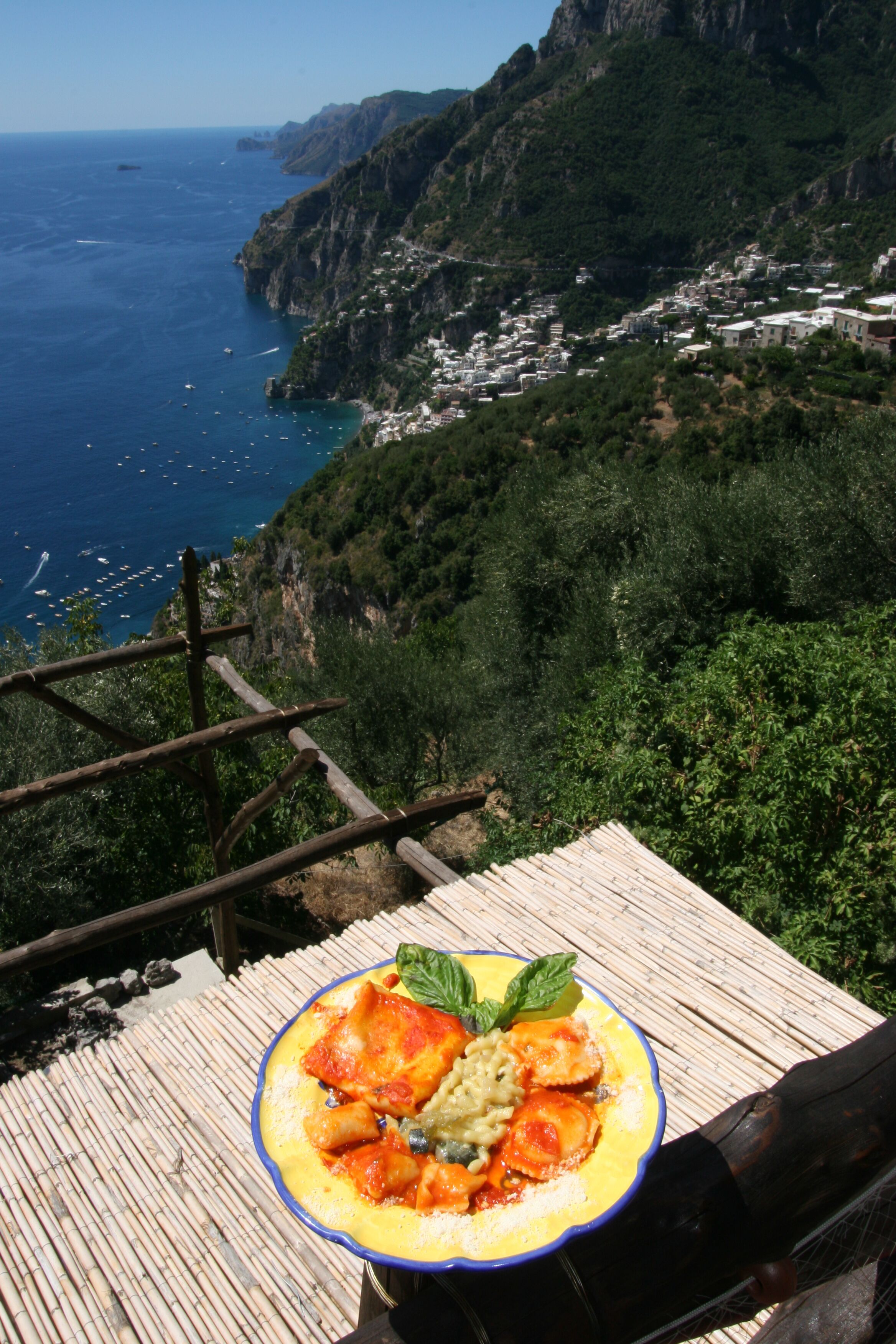 Vista panorámica de la costa con una terraza de madera y un plato de comida.