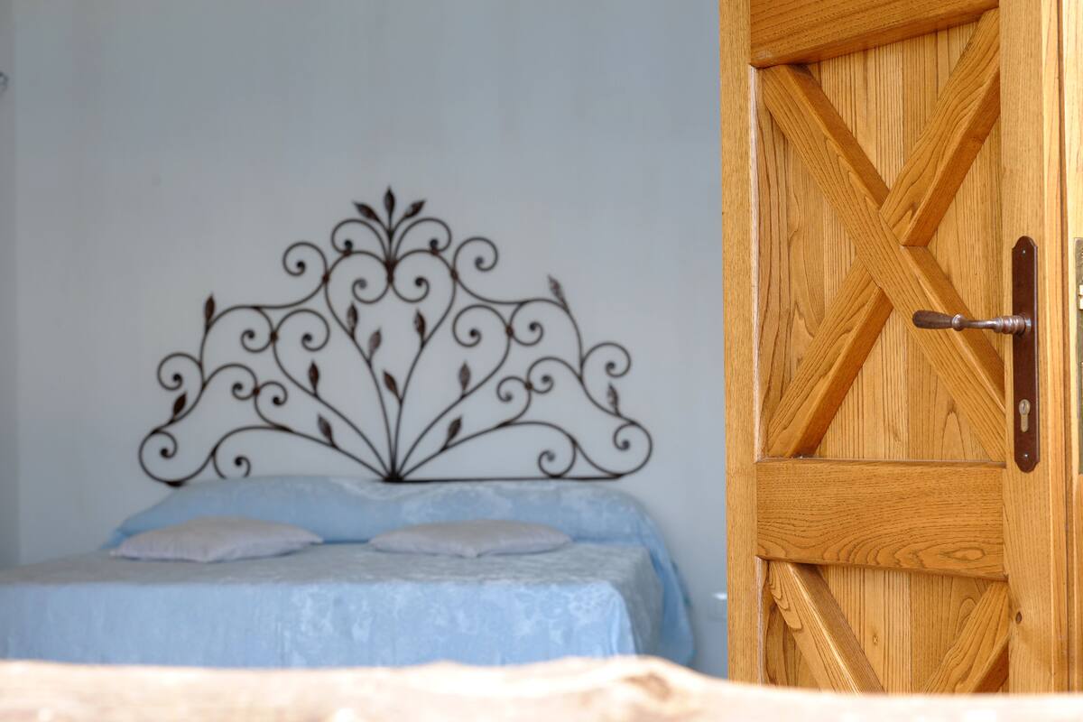 A bedroom with a bed, a wooden door, and a metal headboard.