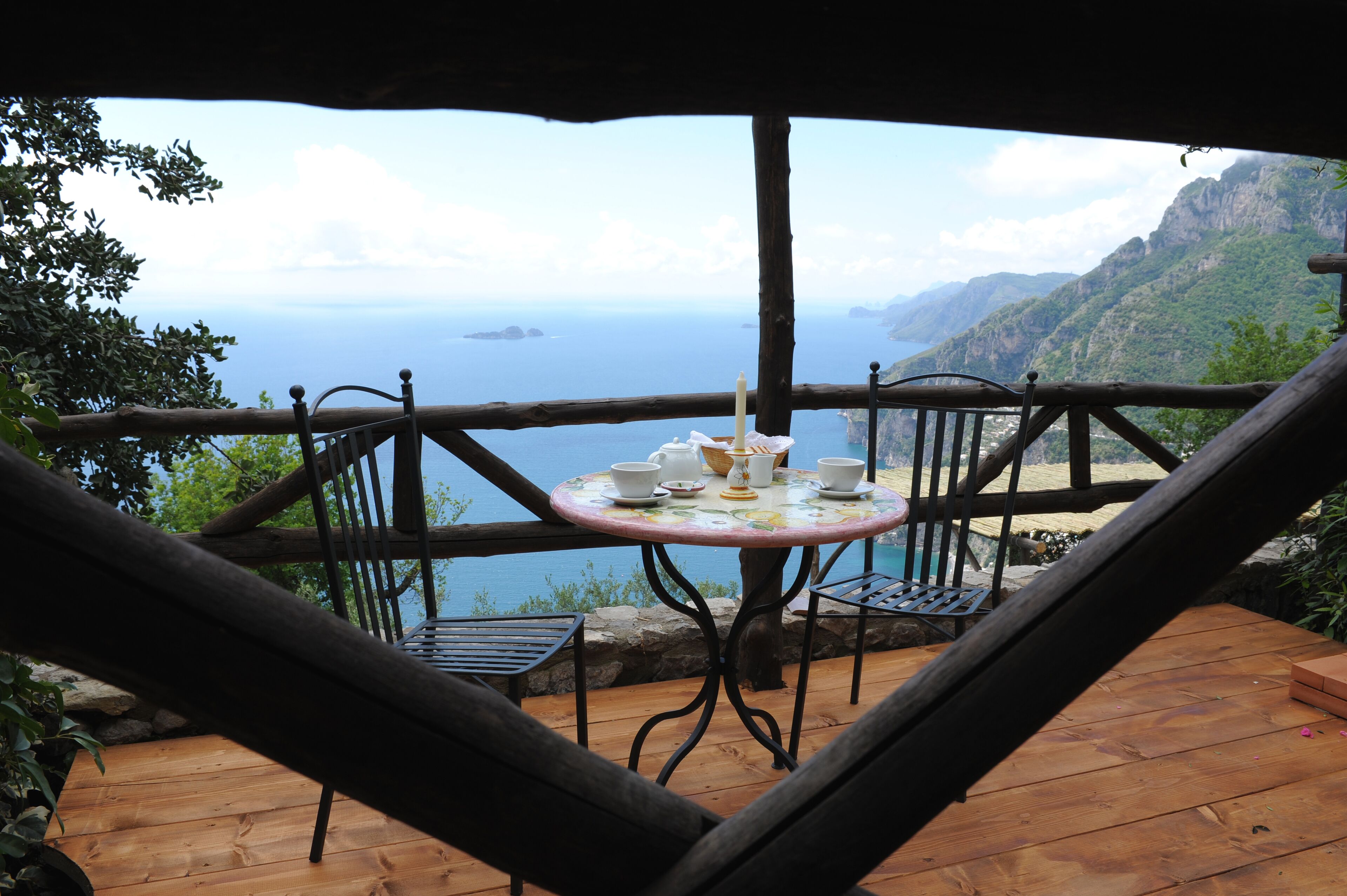 A wooden deck with a table and chairs overlooking a scenic ocean view.