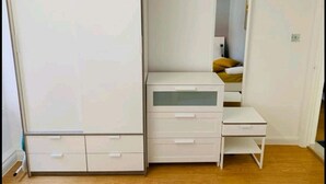 Une chambre à coucher avec une armoire, une table de chevet et un miroir.