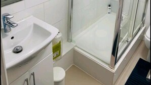 Une salle de bain avec une douche à parois de verre, un lavabo et des toilettes.
