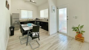 A modern kitchen with a dining area, a ceiling fan, and a potted plant.