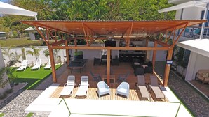 A covered outdoor area with a ping pong table, lounge chairs, and a dining table with chairs.