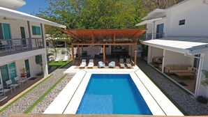 A modern pool area with a wooden pergola, lounge chairs, and a clear blue pool.