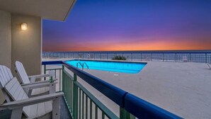 A pool with a sunset view, a balcony with chairs, and a railing. - Oceans 415-Spacious Oceanfront 1BR- Outdoor Pool (North Myrtle Beach)