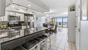 A modern kitchen with a large island, stainless steel appliances, and a dining area with a view. - Oceans 415-Spacious Oceanfront 1BR- Outdoor Pool (North Myrtle Beach)
