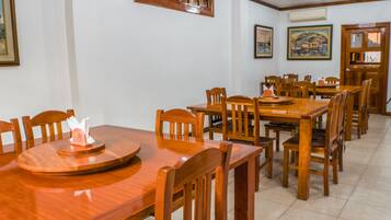 A dining area with wooden tables and chairs, framed artwork on the walls, and a door with a sign.