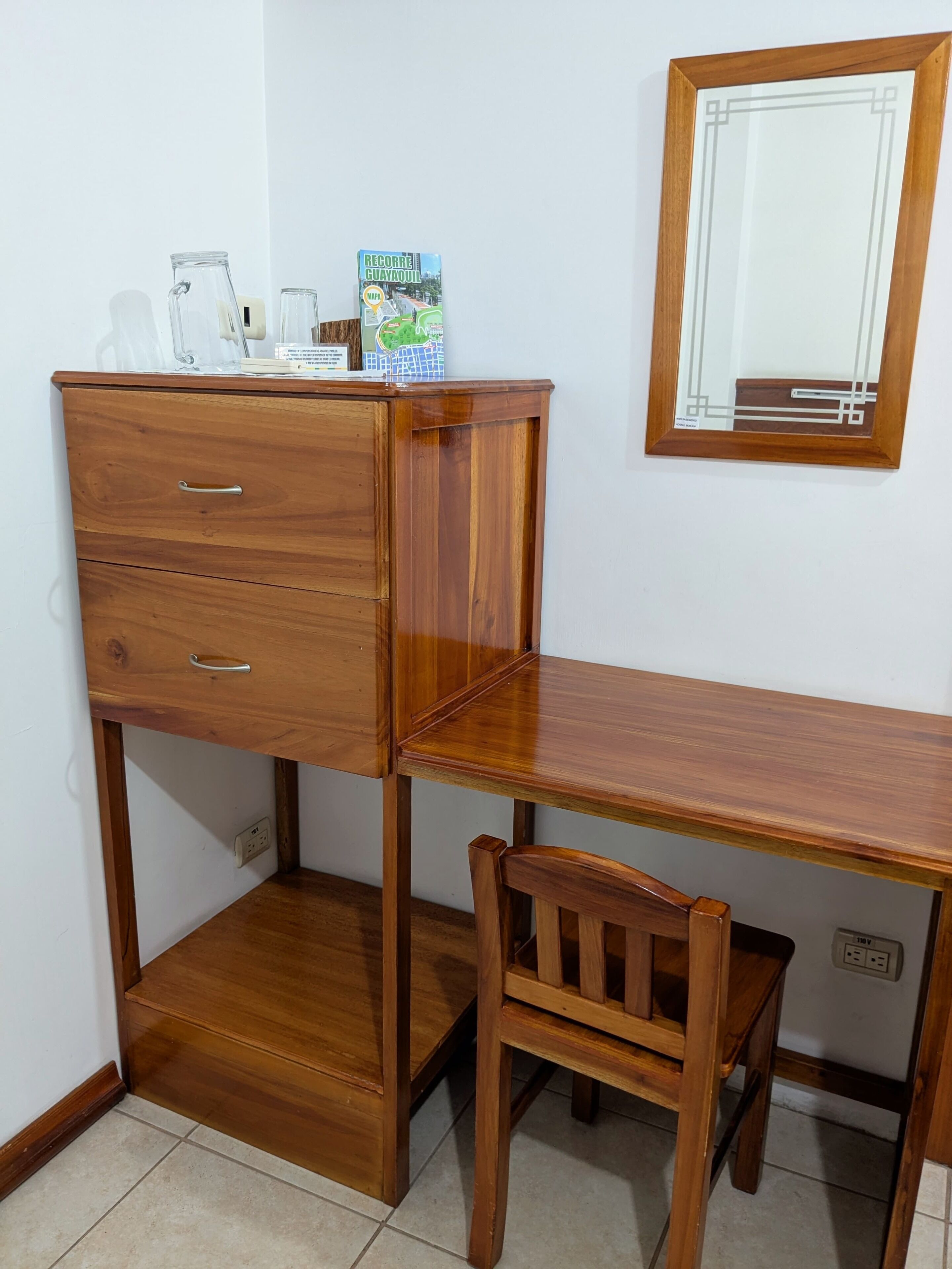 Un escritorio de madera con una silla, un espejo y un mapa sobre el escritorio.