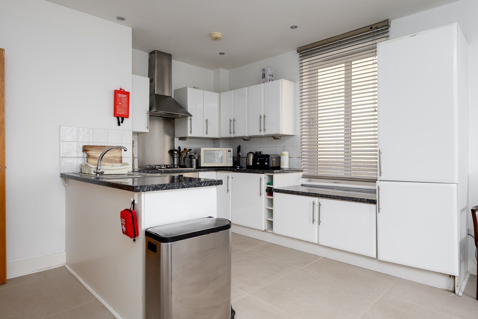 Una cocina moderna con armarios blancos, una campana de acero inoxidable, un microondas y un horno empotrado.