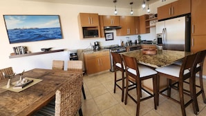 Une cuisine moderne avec des meubles en bois, un îlot central doté de tabourets, une cuisinière et un réfrigérateur.