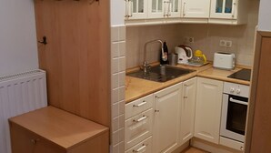 Una cucina compatta con mobili bianchi, forno integrato e lavello.