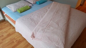 Un letto con una coperta e dei cuscini a fantasia, un pavimento in legno e una testiera.