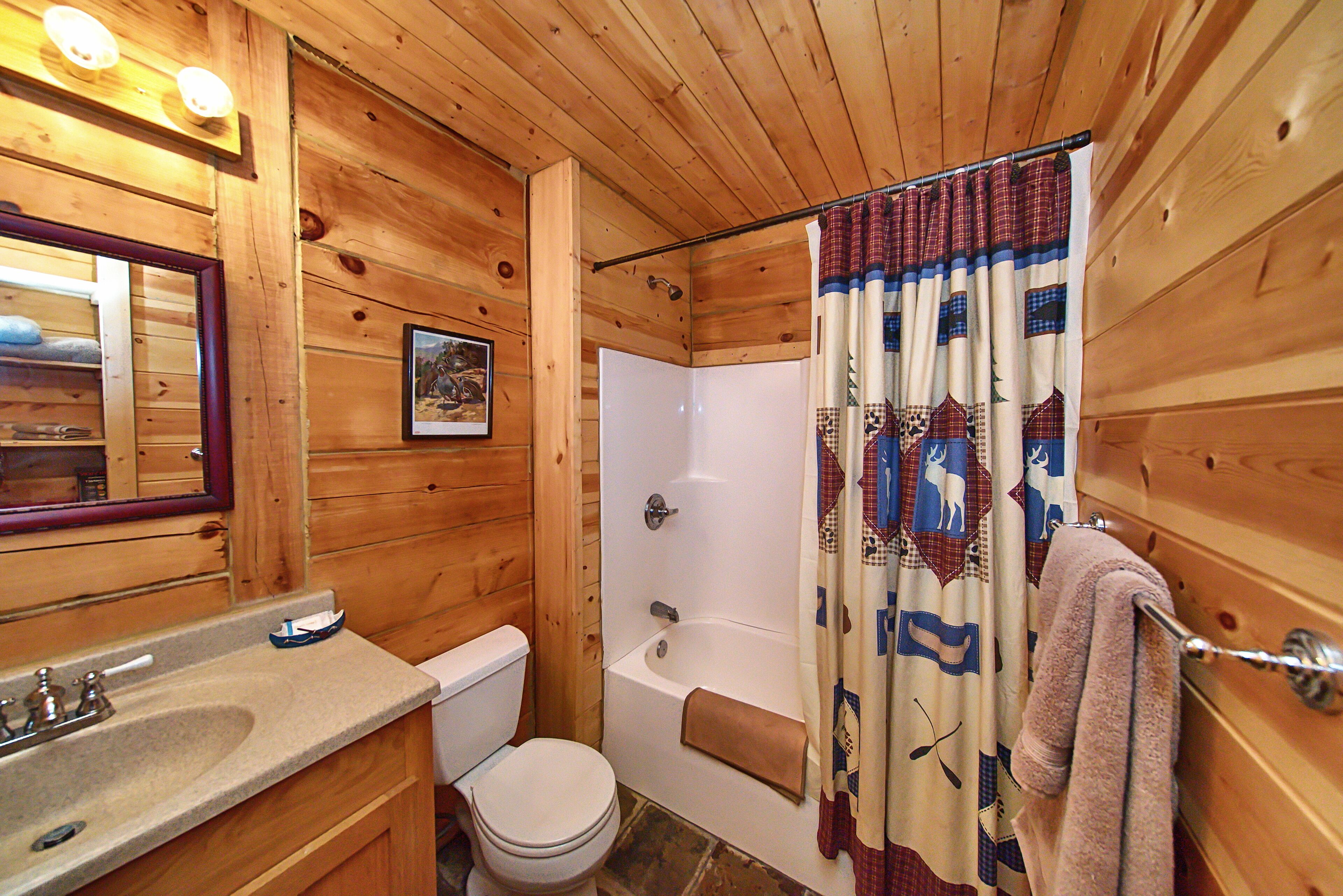 A wooden cabin bathroom with a sink, toilet, and bathtub.