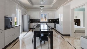 Una cocina moderna con un amplio comedor, armarios blancos y vistas al exterior a través de una ventana.