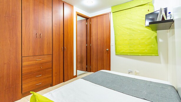 Une chambre à coucher avec un lit, une armoire en bois et un rideau vert.