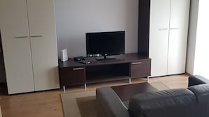 Een moderne woonkamer met een bank, een televisie op een houten dressoir en een kast.