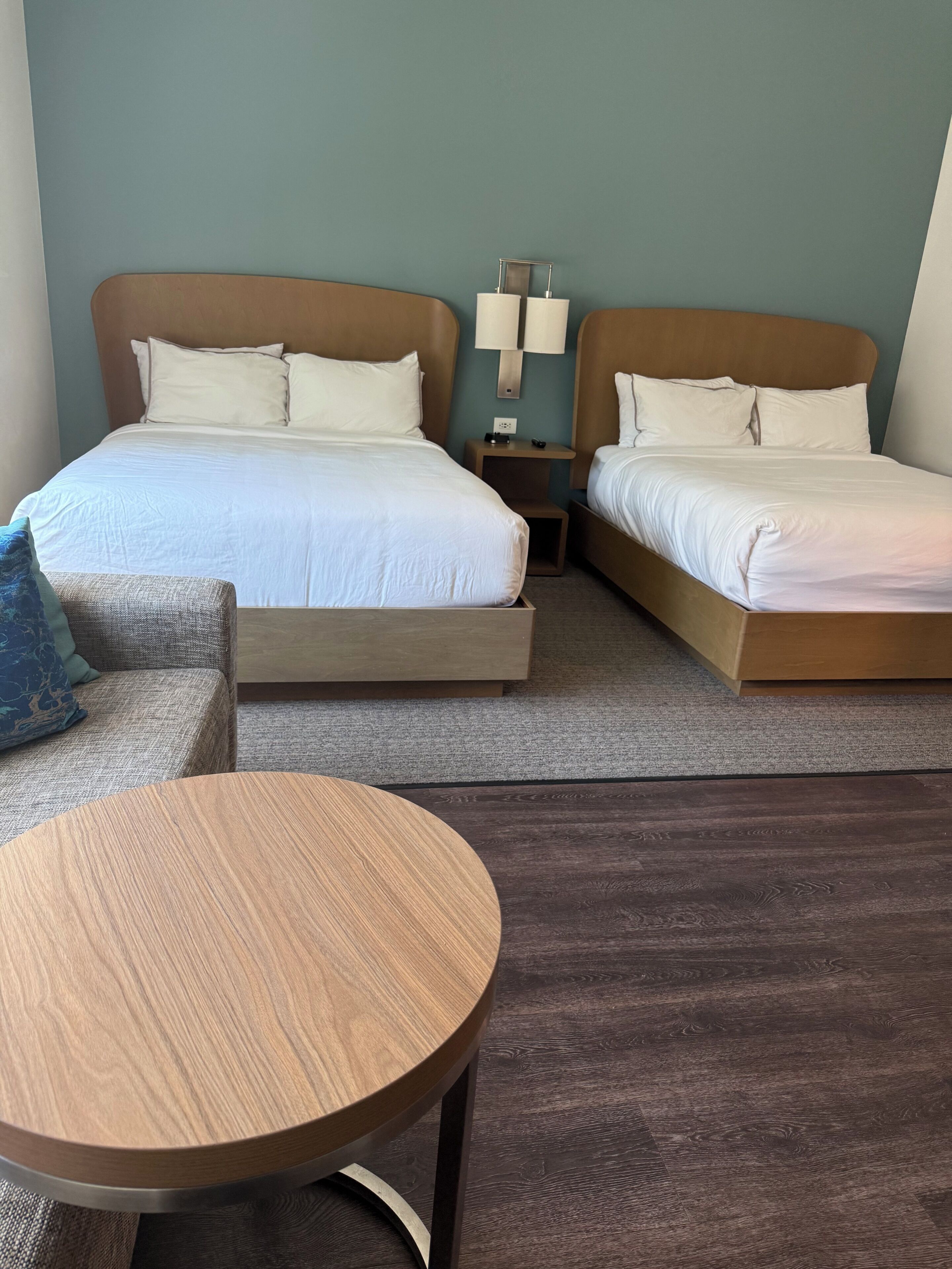 A hotel room with two beds, a small table, and a sofa.