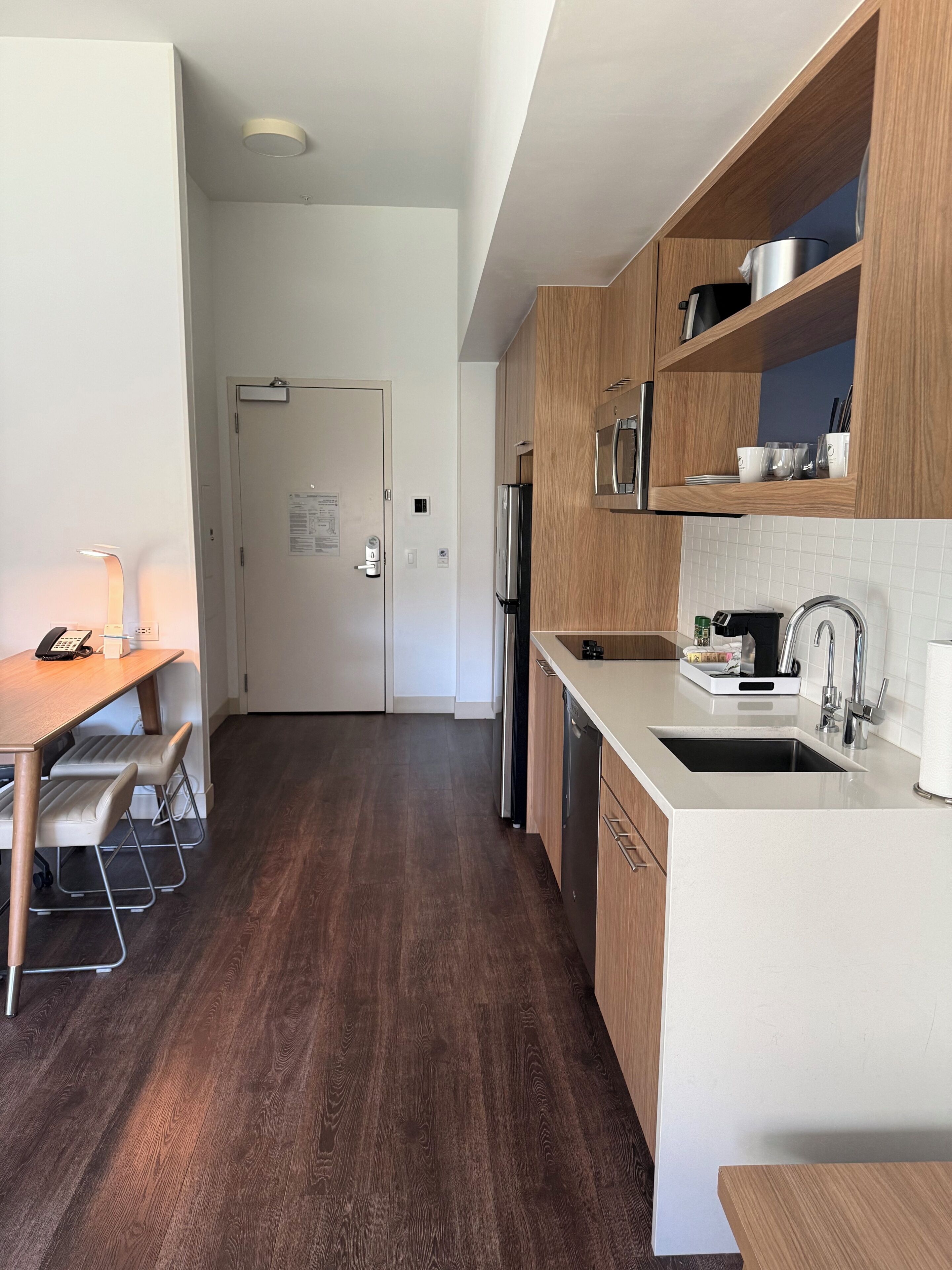 A modern kitchen with wooden cabinets, a stainless steel refrigerator, and a white countertop.