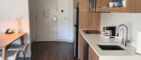 A modern kitchen with wooden cabinets, a stainless steel refrigerator, and a white countertop.