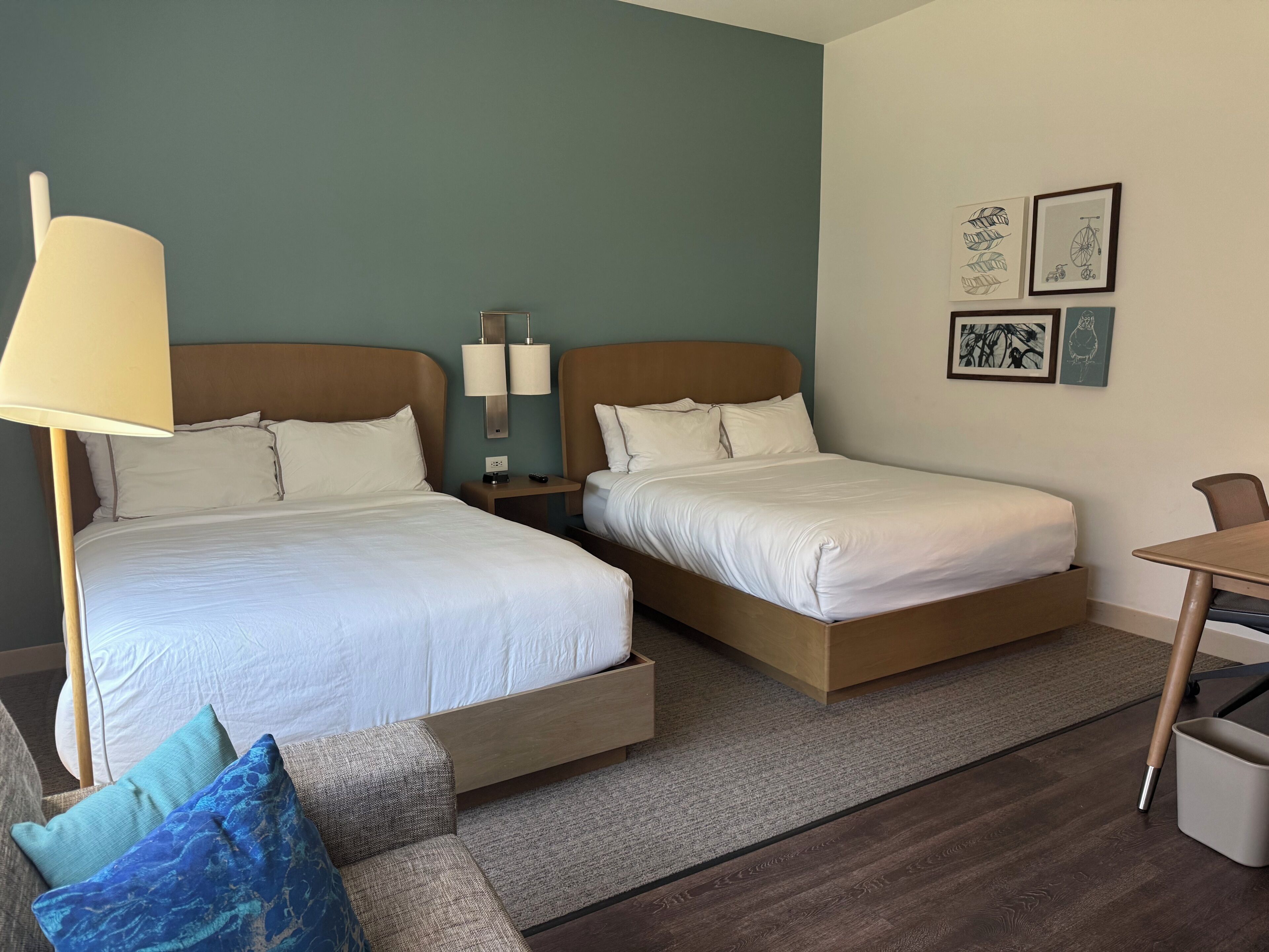 A hotel room with two beds, a desk, and a chair.