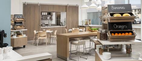 Una cocina moderna con una isla central, una barra de desayuno y una exhibición de frutas con plátanos y naranjas.