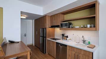 A compact kitchen with wooden cabinets, stainless steel appliances, and a white countertop.