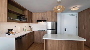 A modern kitchen with wooden cabinets, a stainless steel refrigerator, and a white countertop.