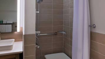 Une salle de bain moderne équipée d’une douche, d’un lavabo et d’un banc.
