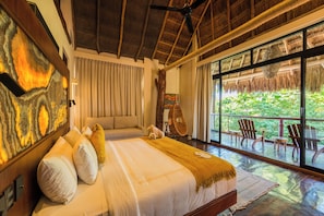 A bedroom with a large bed, a ceiling fan, a view through the window, and a wooden ceiling. - Casa Teka (Tulum)