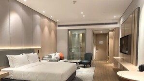 Een moderne hotelkamer met een groot bed, een bureau, een stoel, een klein tafeltje en een televisie.