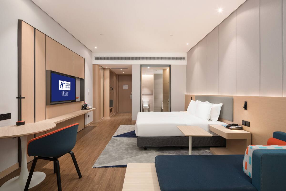 Habitació d'hotel moderna amb llit, escriptori, cadira i televisió.
