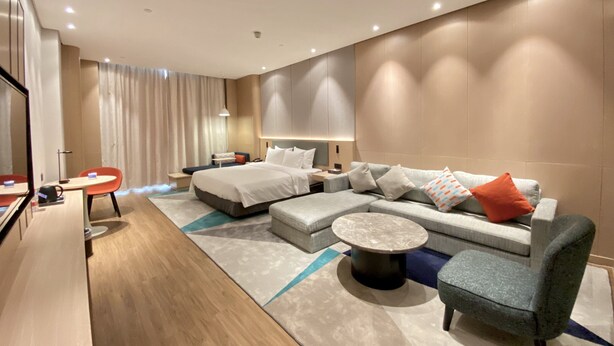 Een moderne hotelkamer met een groot bed, een bank, een salontafel en een bureau met een stoel.