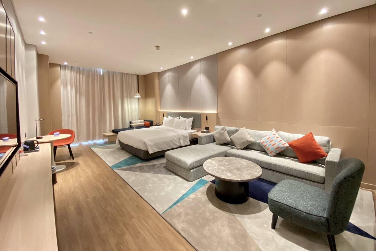 Una habitació d'hotel moderna amb un llit gran, un sofà, una taula de cafè i un escriptori amb una cadira.
