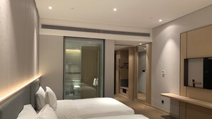 Een moderne hotelkamer met een groot bed, een inloopkast en een aan de muur bevestigde televisie.