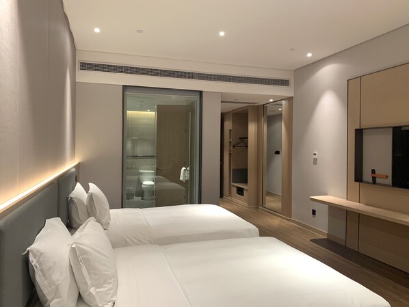 Ein modernes Hotelzimmer mit einem großen Bett, einem begehbaren Kleiderschrank und einem an der Wand befestigten Fernseher.
