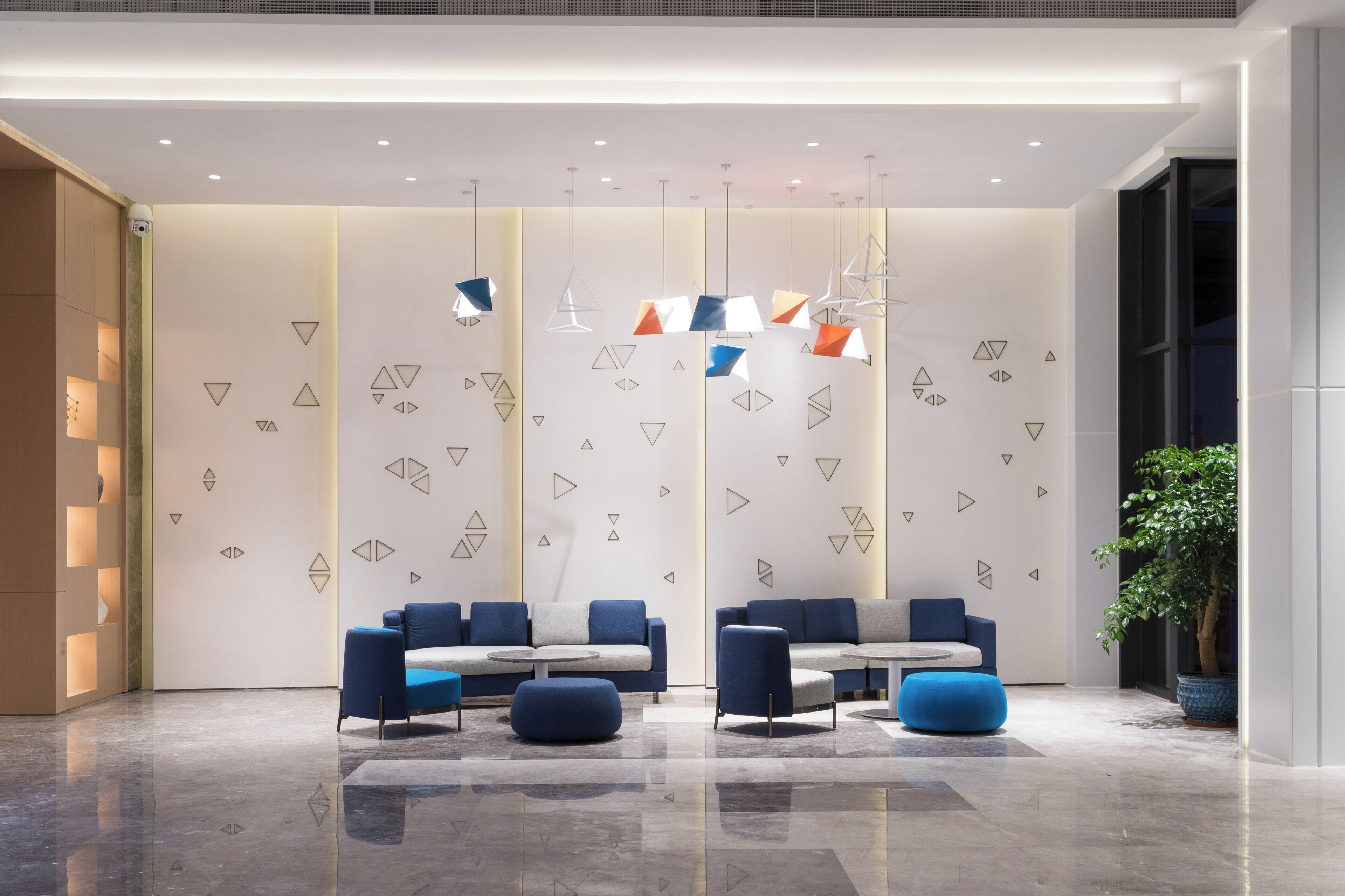 En moderne lobby med siddeområde, geometriske vægmønstre og hængende lys.