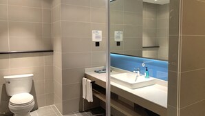 Een moderne badkamer met toilet, wastafel en grote spiegel.