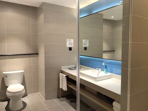 A modern bathroom with a toilet, sink, and large mirror.
